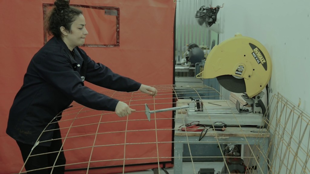 Still from Exile Echoes (2024) by Mazyar Mahan: an artist cuts steel rods in her studio