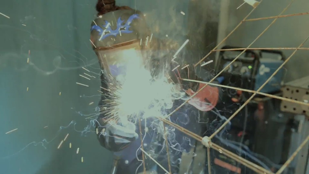 Still from Exile Echoes (2024) by Mazyar Mahan: sparks fly as a metal frame is welded