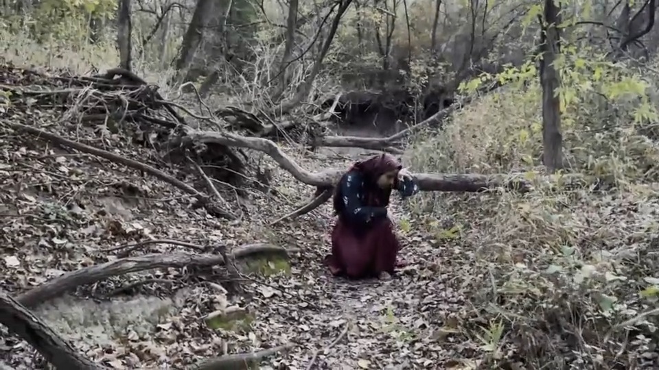 Still from Fear (2021) by Mazyar Mahan: the dancer bows low among the roots of an uprooted tree.