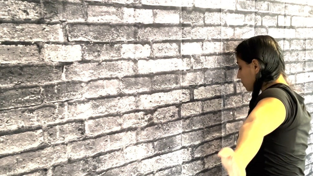 Still from For Freedom (2022) by Mazyar Mahan: the dancer turns her back, facing the brick wall.