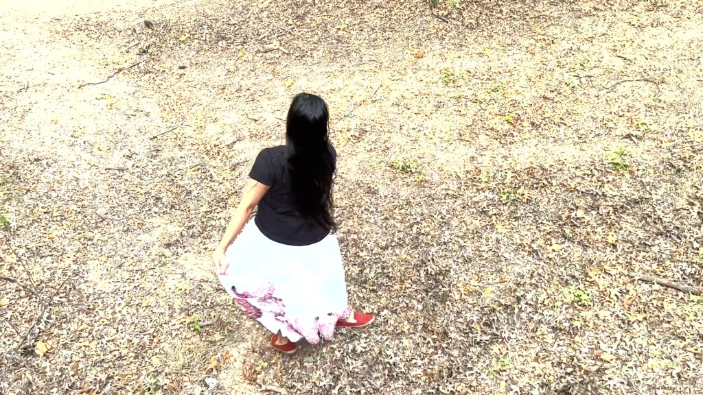 Still from For Freedom (2022) by Mazyar Mahan: the dancer spins, her white skirt flaring over the dry ground.