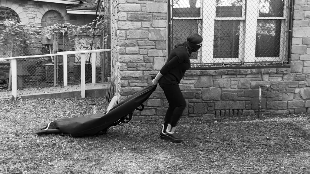 Still from Return of the Repressed (2023) by Mazyar Mahan: a woman drags a black chador across the ground